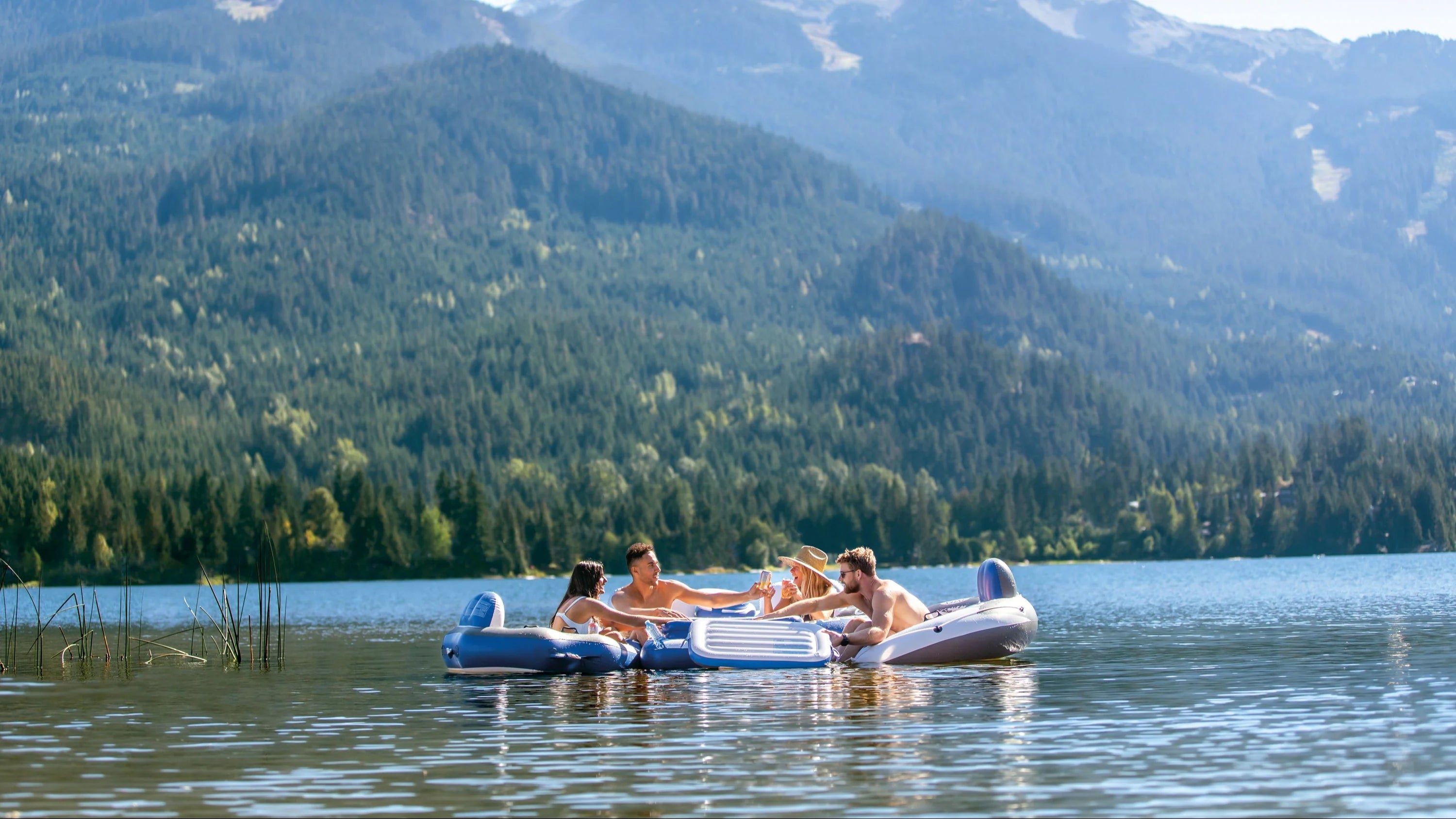 People on inflatable rafts in a lake with mountains in the background